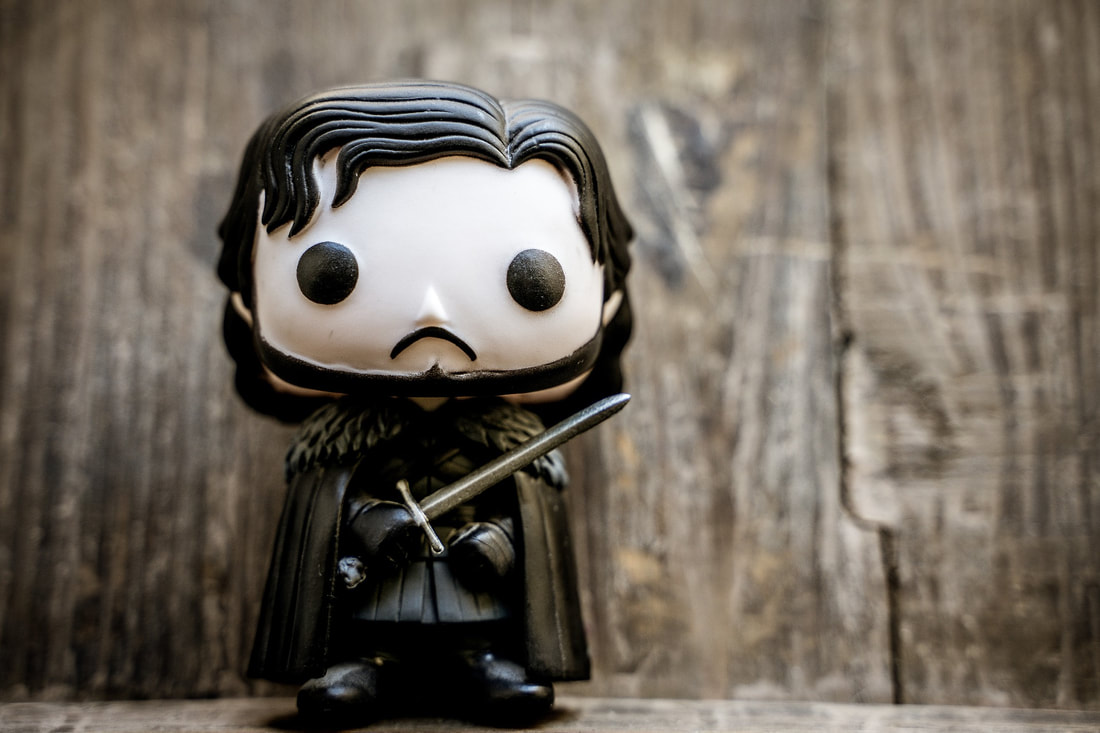 Toy figure of Jon Snow is kept against a wall with a wood panel background.